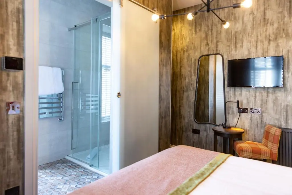 a bedroom with a shower and a bed and a mirror at Hotel 1881 of Speyside in Archiestown