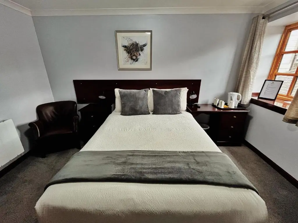 a bedroom with a large bed and a chair at The Stag Hotel in Banchory