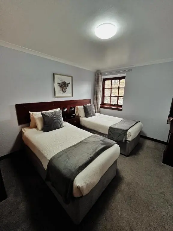 a hotel room with two beds and a window at The Stag Hotel in Banchory