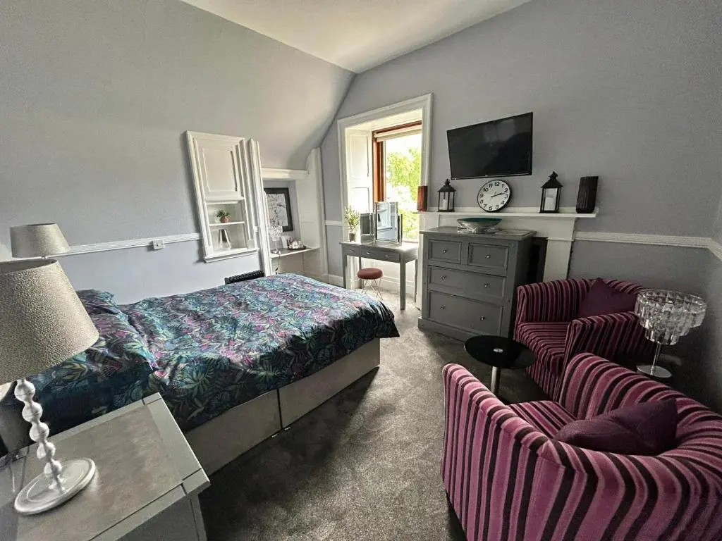 a bedroom with a bed and a desk and two chairs at St Duthus Hotel in Tain