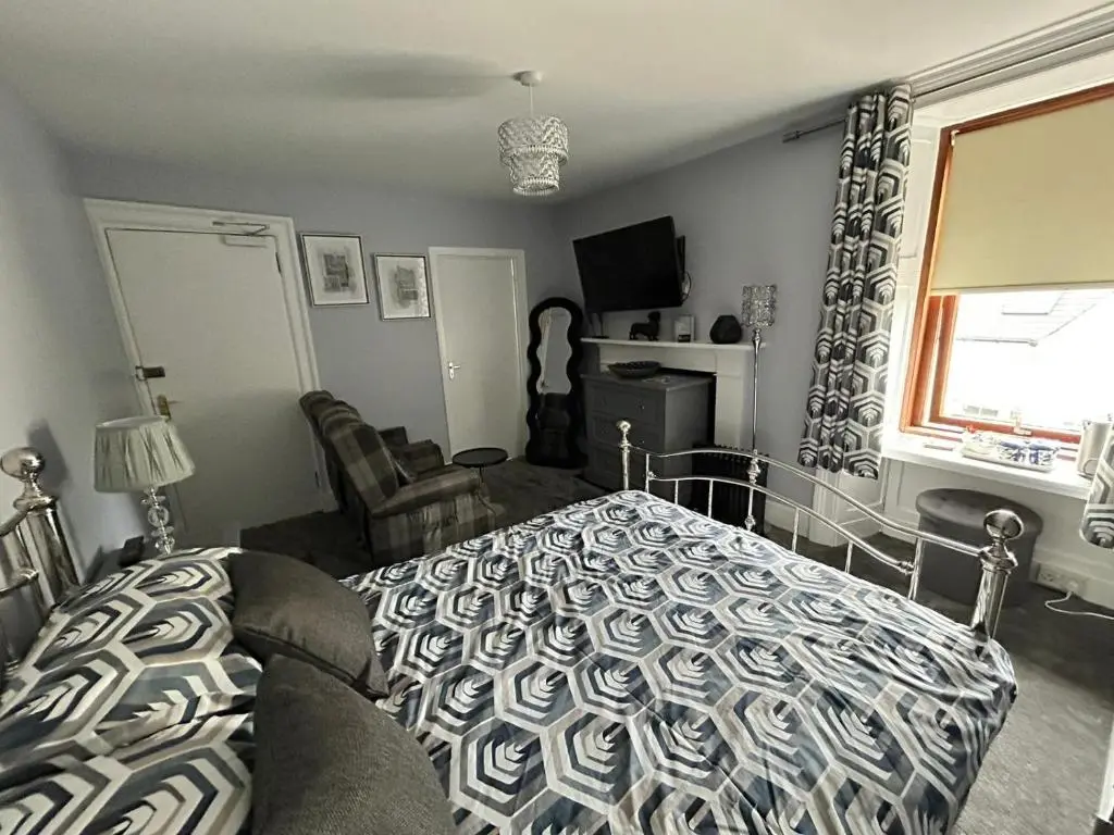 a bedroom with a bed and a couch and a window at St Duthus Hotel in Tain