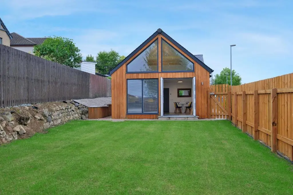 a wooden house with a lawn in front of it at Contemporary Luxury Lodge, Aberdeen West in Blackburn