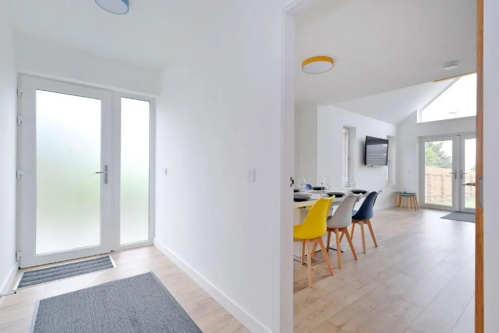 a dining room with white walls and a table with yellow chairs at Contemporary Luxury Lodge, Aberdeen West in Blackburn
