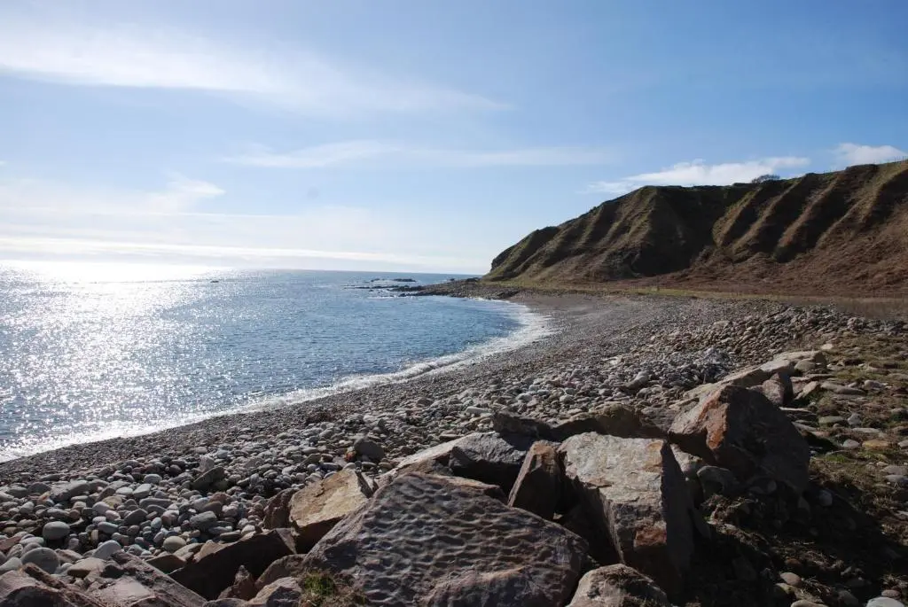 a rocky beach with the ocean in the background at Turadh 'a break in the clouds' in Dunbeath