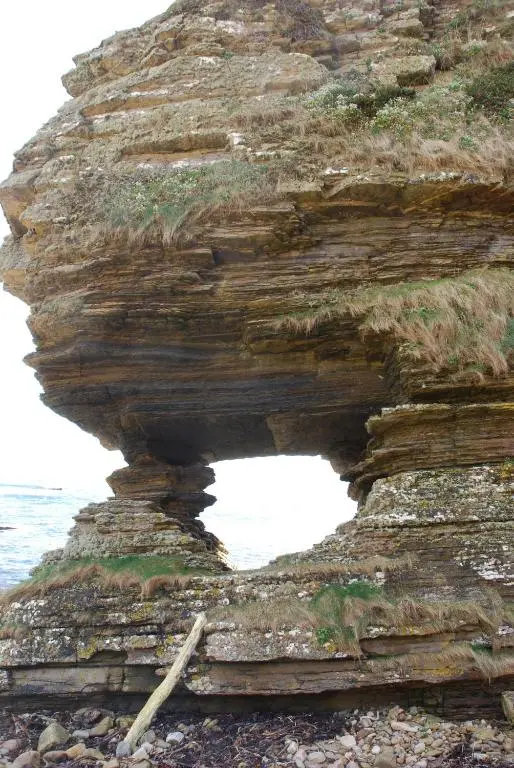 a rock formation on the beach near the ocean at Turadh 'a break in the clouds' in Dunbeath