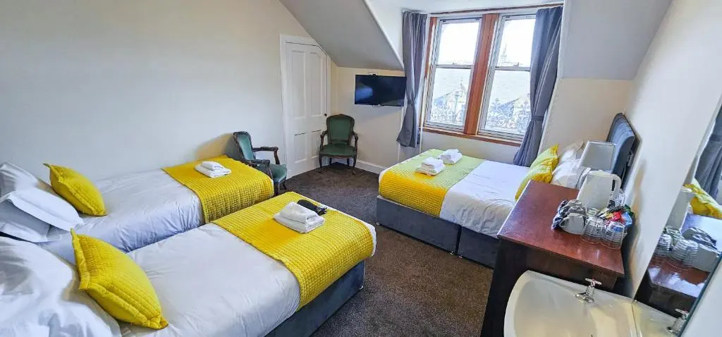 a hotel room with two beds and a sink at Melrose Villa 11 Bedroom House in Inverness
