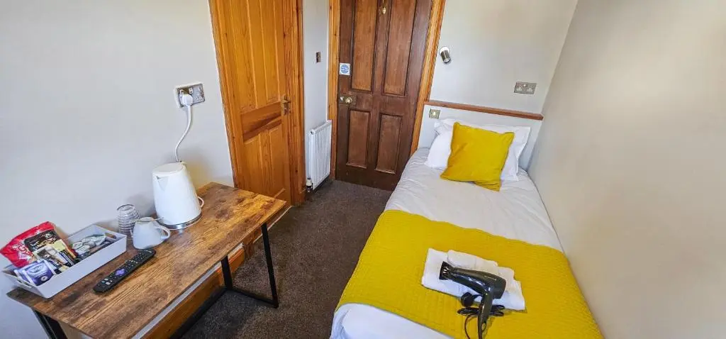 a small room with a bed and a desk with a phone at Melrose Villa 11 Bedroom House in Inverness