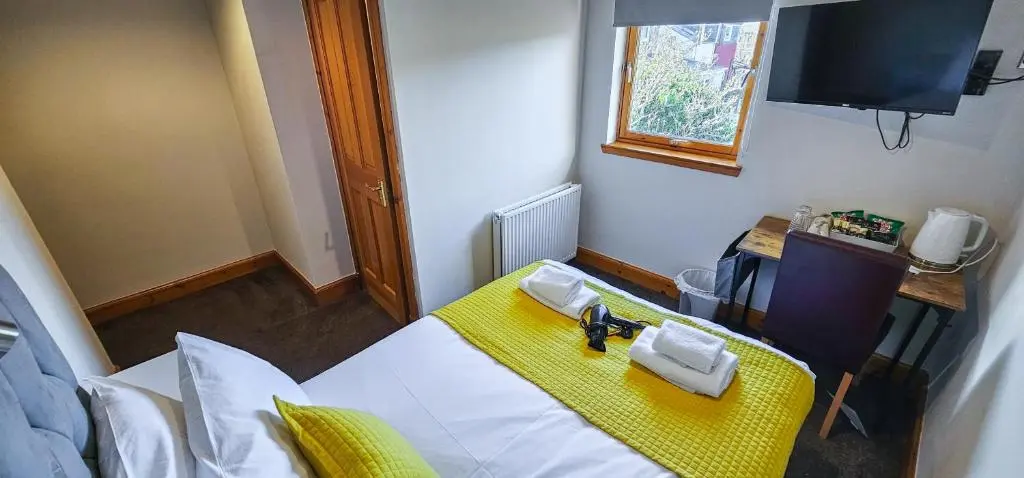 a room with a bed with a yellow table and a television at Melrose Villa 11 Bedroom House in Inverness
