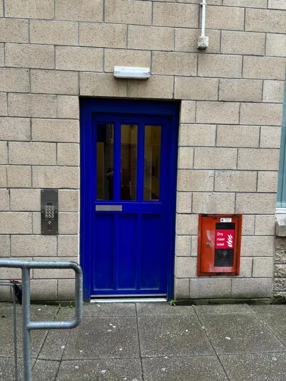 a blue door on the side of a brick building at MacIver City Apartments Farraline Court in Inverness