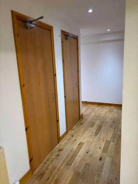 an empty room with two doors and wooden floors at MacIver City Apartments Farraline Court in Inverness