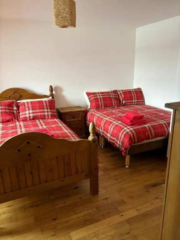 a bedroom with two beds and a couch at MacIver City Apartments Farraline Court in Inverness