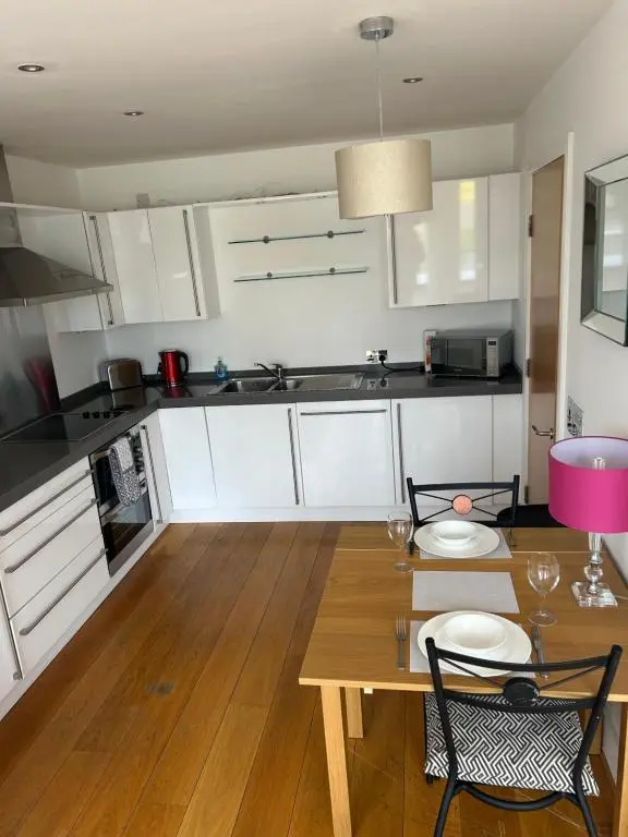 a kitchen with white cabinets and a wooden table at 1 Bedroom Castleview Apartment 404-Free Parking in Inverness