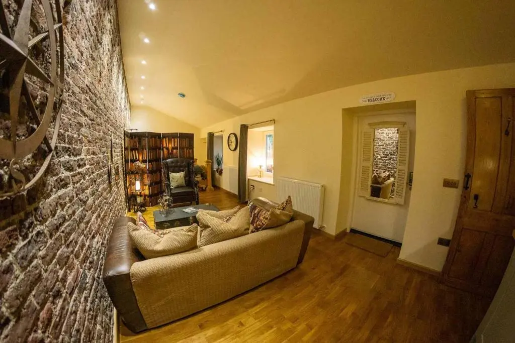 a living room with a couch and a brick wall at The Potted Pineapple in Oyne