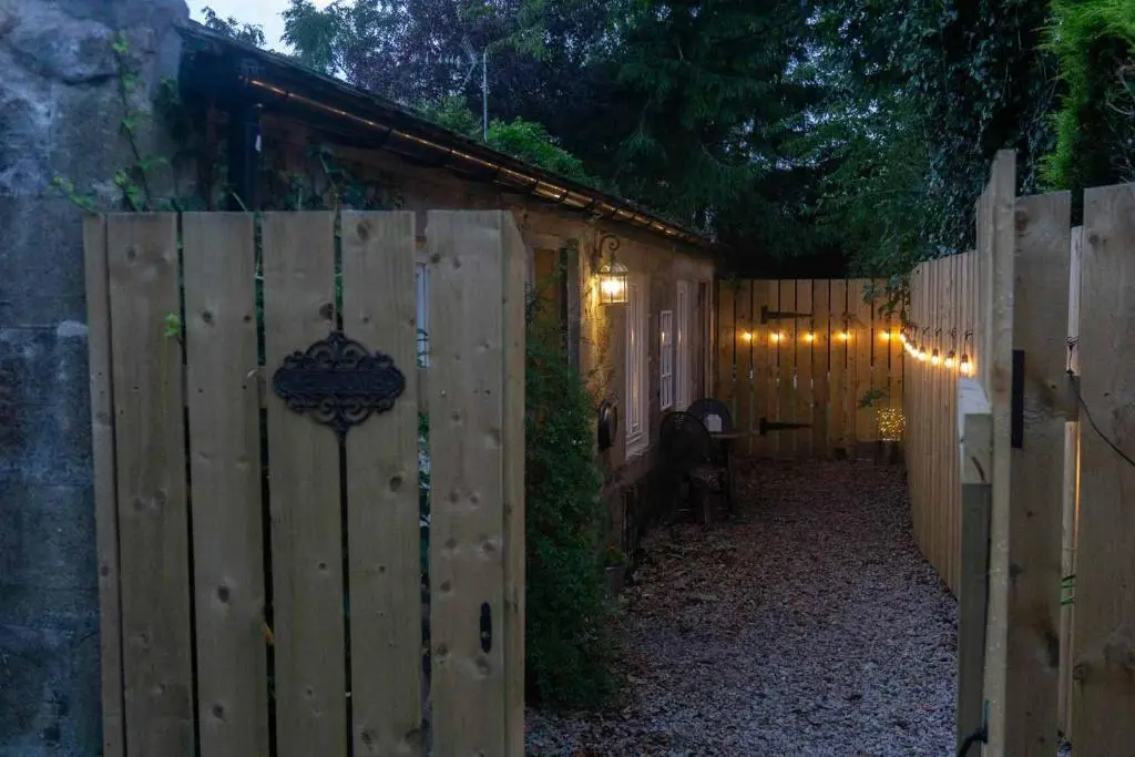 a wooden fence with a gate in a backyard at night at The Potted Pineapple in Oyne