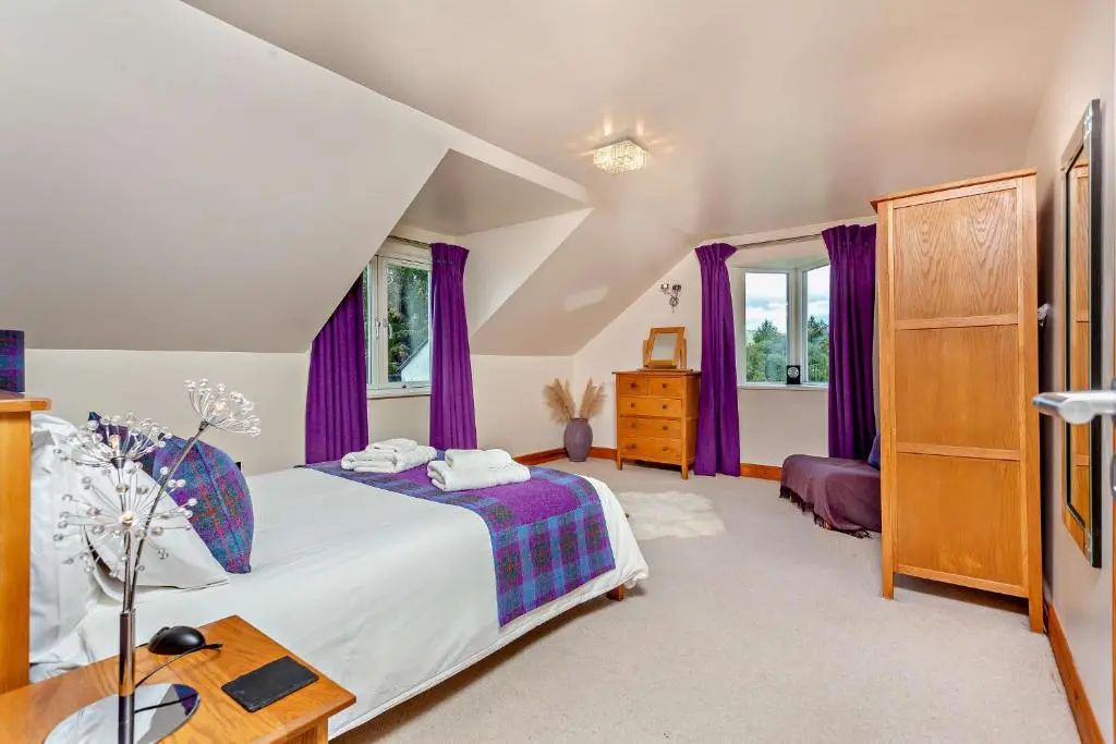 a bedroom with a bed and purple curtains at Sealladh an Loch in Foyers