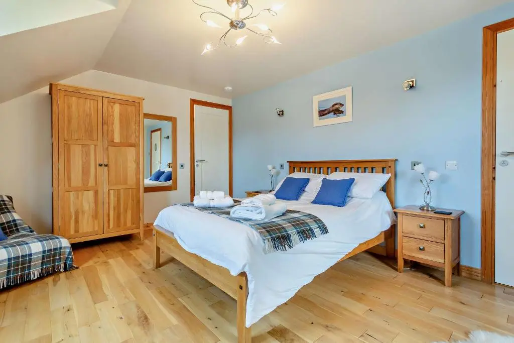 a bedroom with a large bed with blue pillows at Sealladh an Loch in Foyers