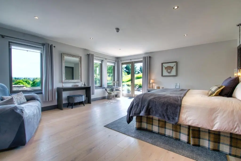 a bedroom with a bed and a desk and windows at Ben Luna Lodge in Inverness