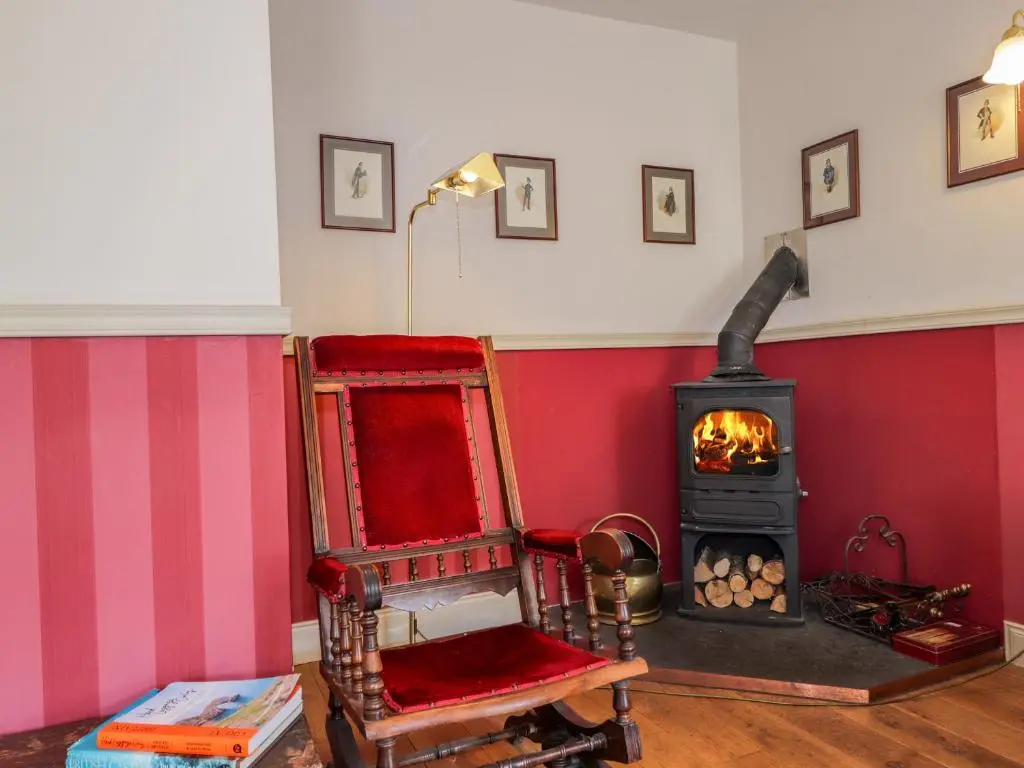 a room with a chair and a wood stove at Seashell Cottage in Cromarty