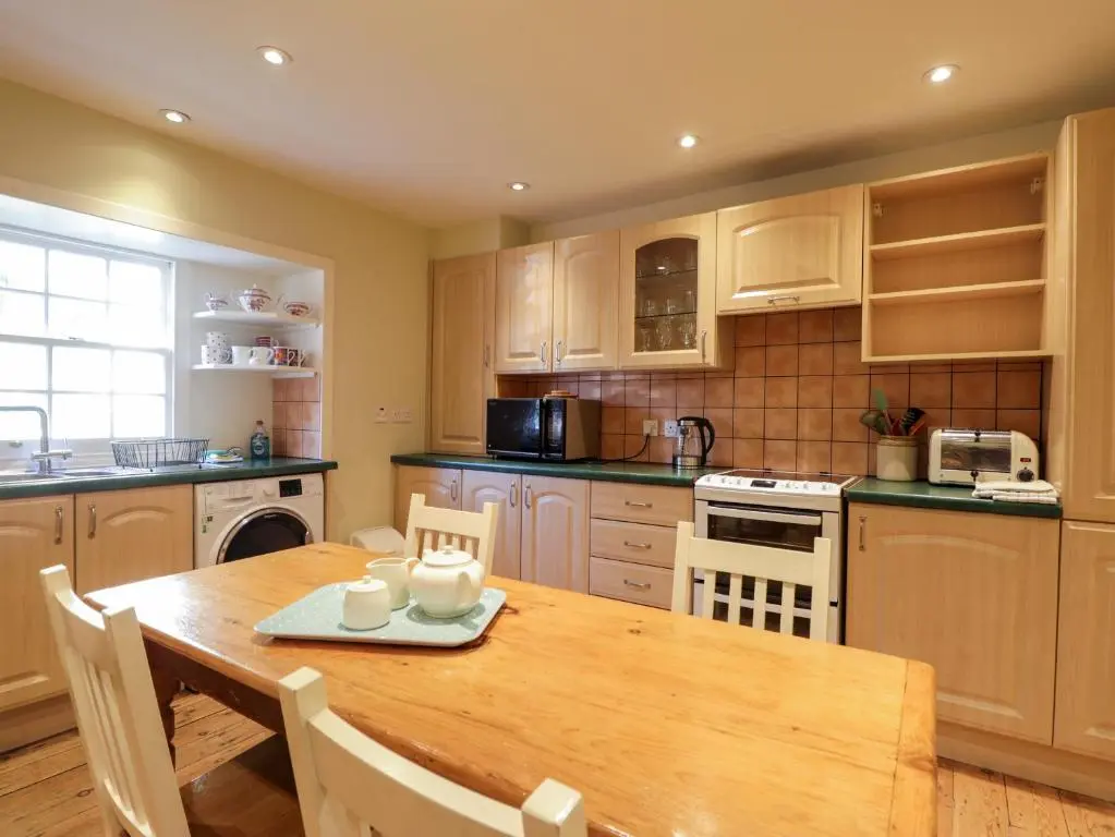 a kitchen with a wooden table and a table and chairs at Seashell Cottage in Cromarty