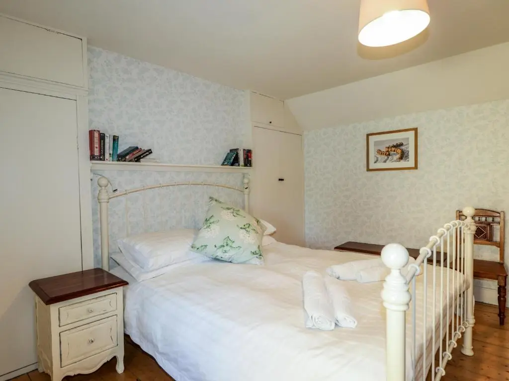 a bedroom with a white bed and a night stand at Seashell Cottage in Cromarty