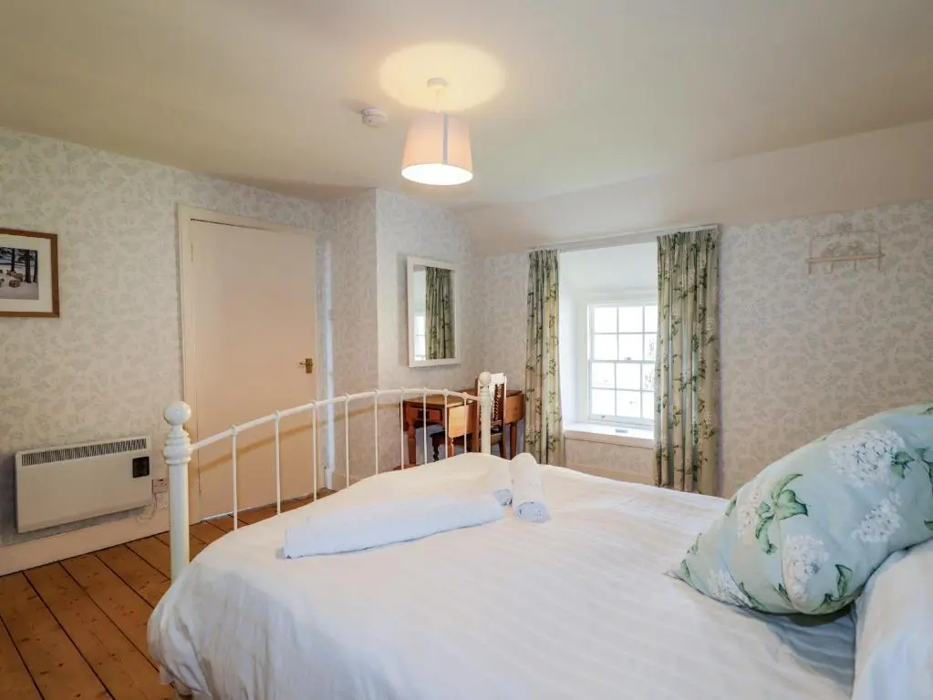 a bedroom with a white bed and a window at Seashell Cottage in Cromarty