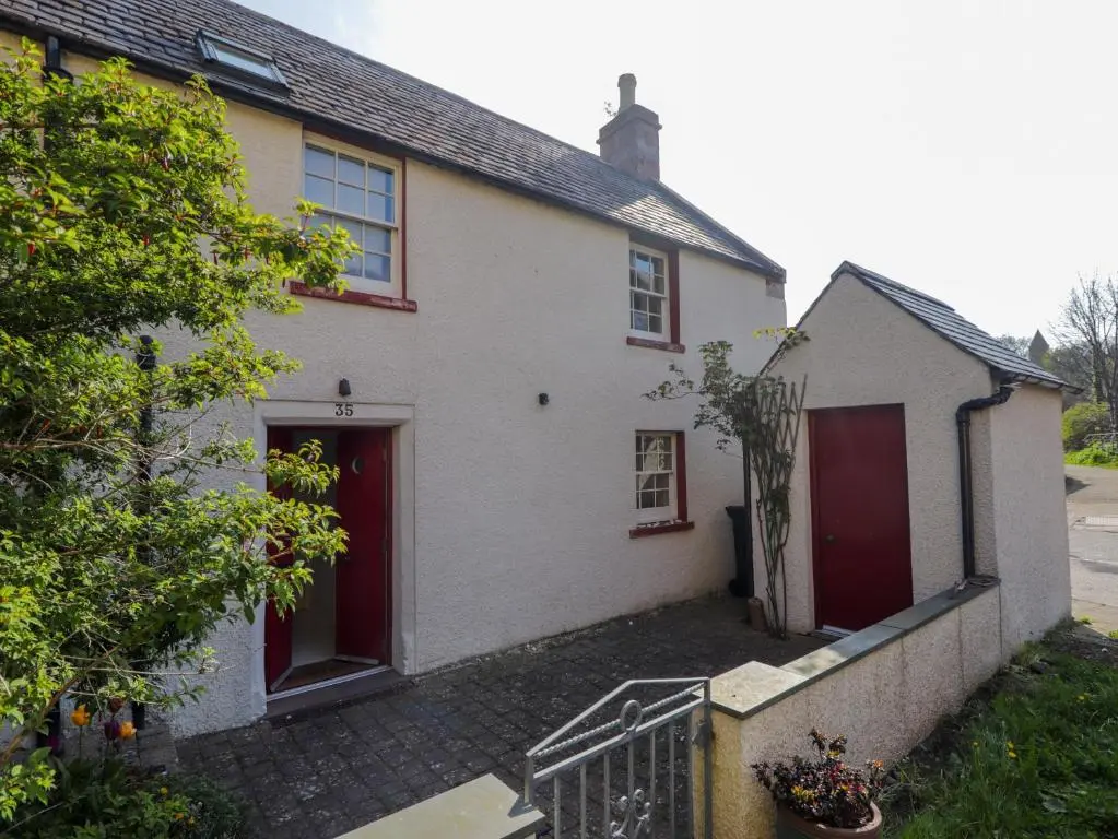 a white house with red doors and a driveway at Seashell Cottage in Cromarty
