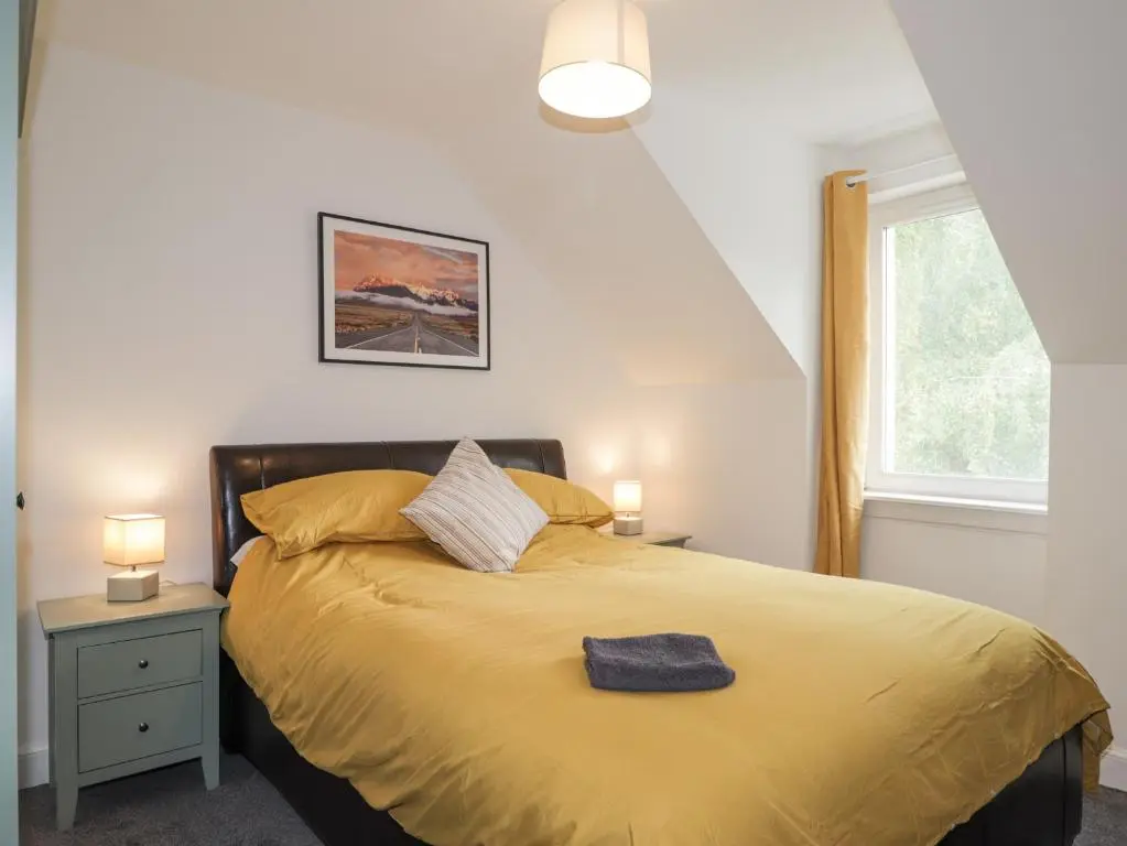 a bedroom with a bed with yellow sheets and a window at Apartment in Foyers in Inverness