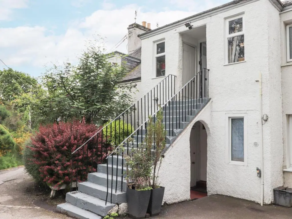 a white house with a staircase in front of it at Apartment in Foyers in Inverness