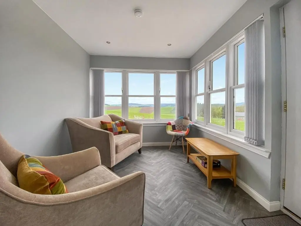 a living room with two chairs and a table and windows at Guise Cottage Uk46303 in Tough
