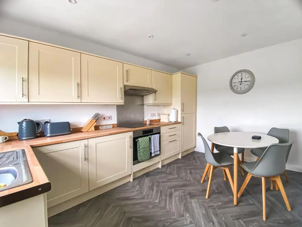 a kitchen with white cabinets and a table and chairs at Guise Cottage Uk46303 in Tough