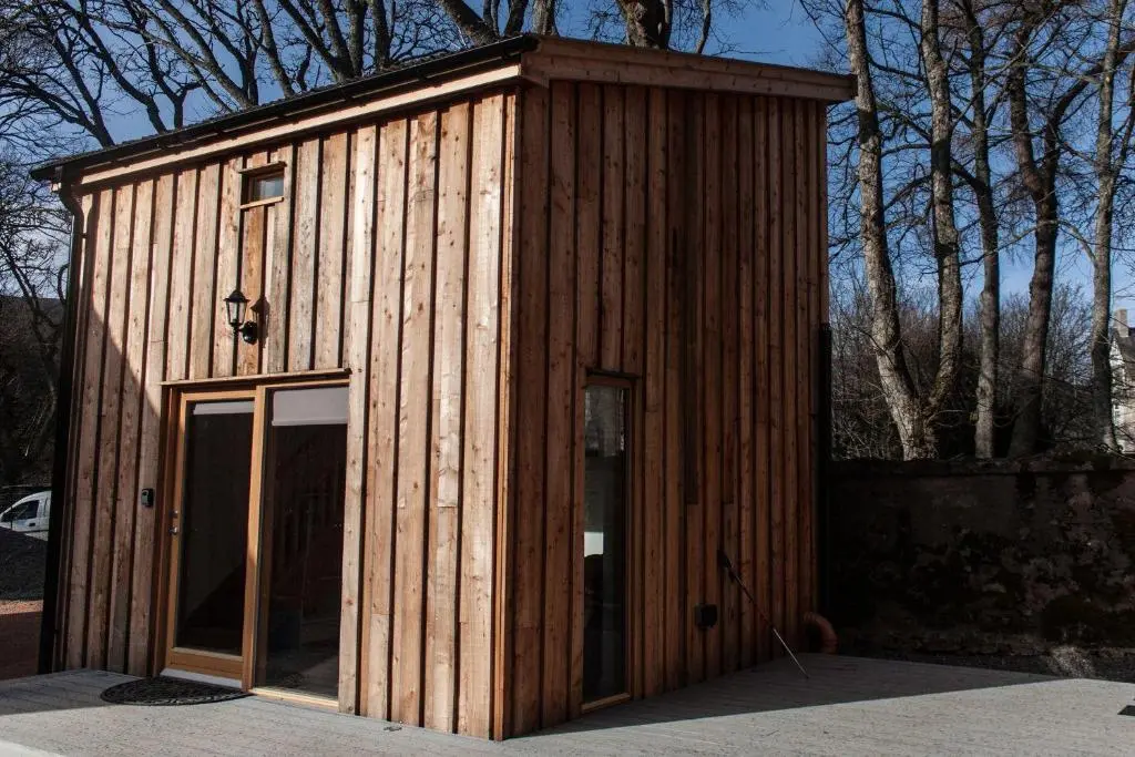 a small wooden building with a glass door at Callater in Braemar