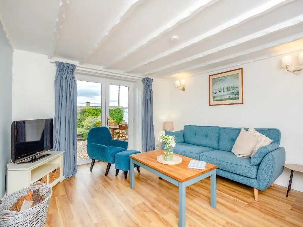 a living room with a blue couch and a table at Emerald Cottage in Burghead