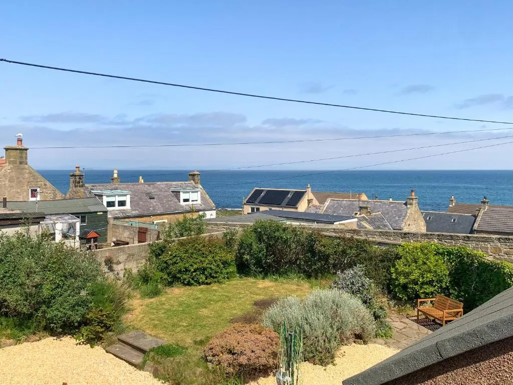 a view of the ocean from the balcony of a house at Emerald Cottage in Burghead