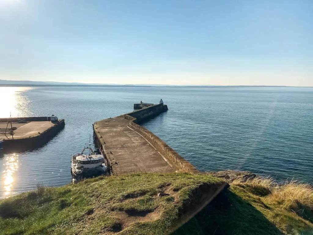 a boat is docked at a dock in the water at Emerald Cottage in Burghead