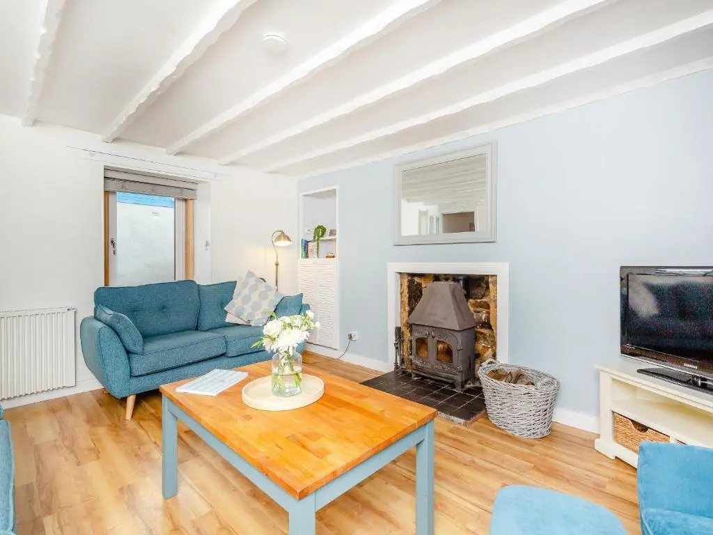 a living room with a blue couch and a fireplace at Emerald Cottage in Burghead