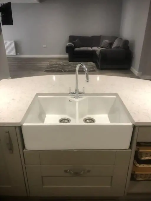 a white sink in a kitchen with a couch at Lisbon 67 in Wick