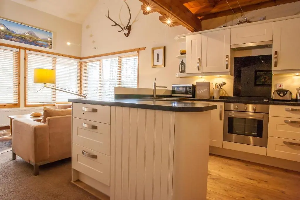 a kitchen with white cabinets and a counter top at Riverside Lodge Garden Apartment in Aviemore