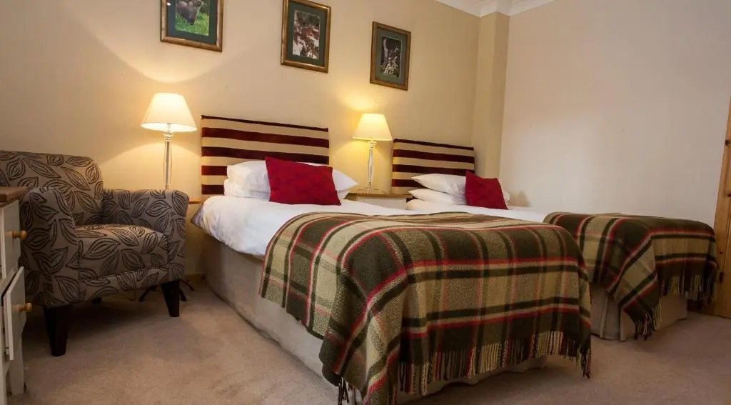 a hotel room with two beds and a chair at Riverside Lodge Garden Apartment in Aviemore