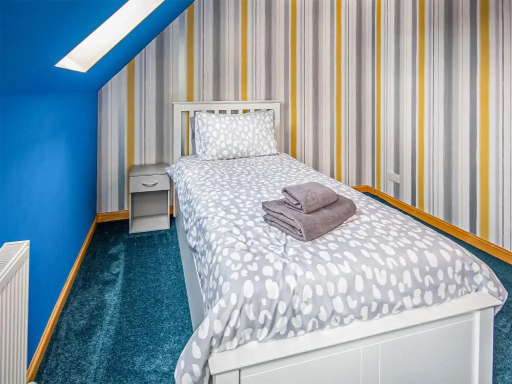 a small bedroom with a bed with a towel on it at Beinn View House in Cononbridge