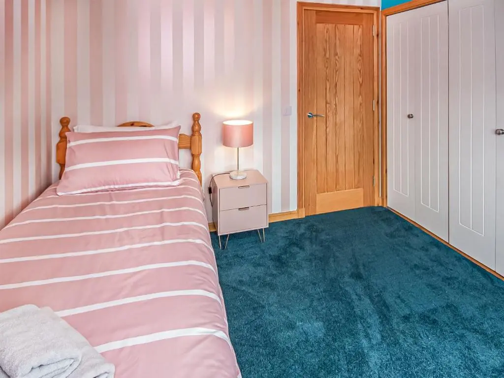 a bedroom with a bed and a table with a lamp at Beinn View House in Cononbridge