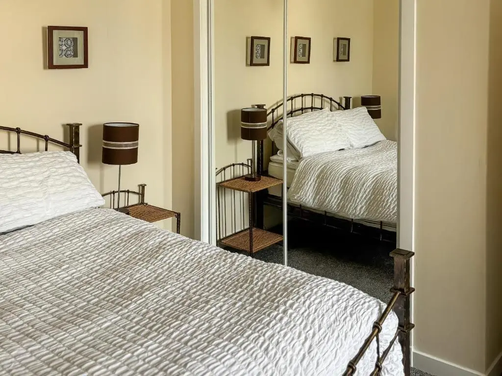 a bedroom with two beds and a mirror at Ivydene Cottage in Cromarty