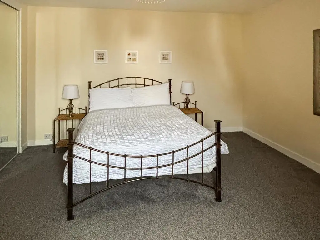 a bedroom with a bed with two nightstands and two lamps at Ivydene Cottage in Cromarty
