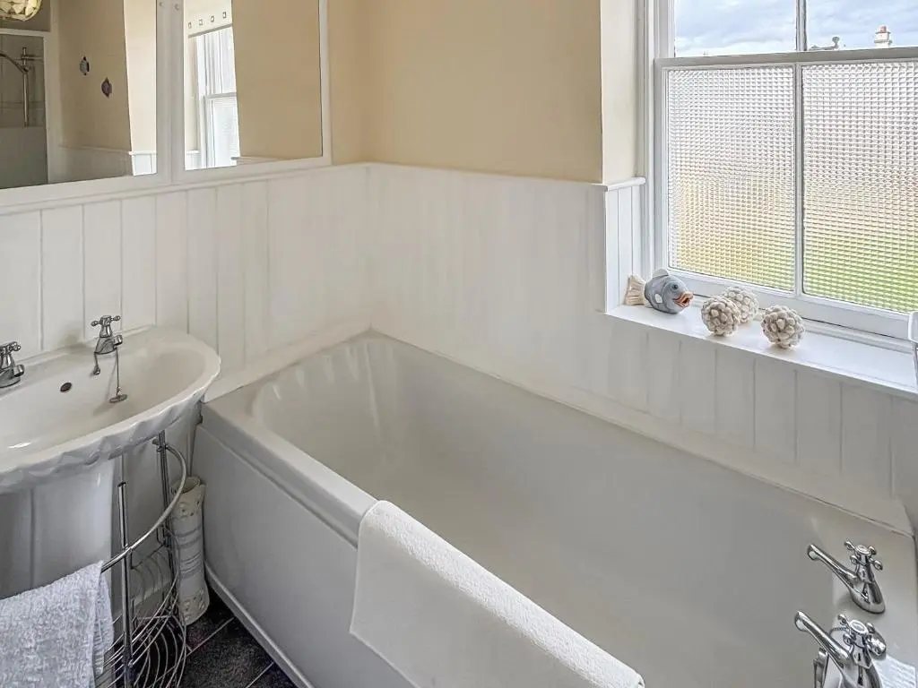 a white bathroom with a tub and a sink at Ivydene Cottage in Cromarty
