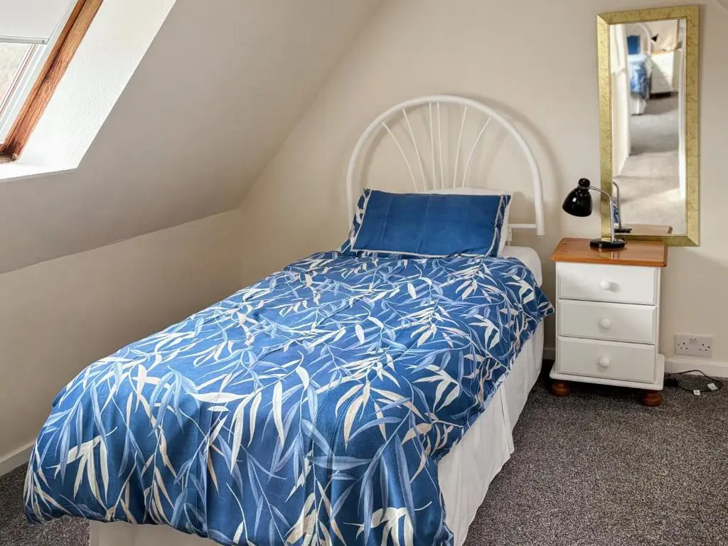 a bedroom with a bed with a blue and white bedspread at Ivydene Cottage in Cromarty