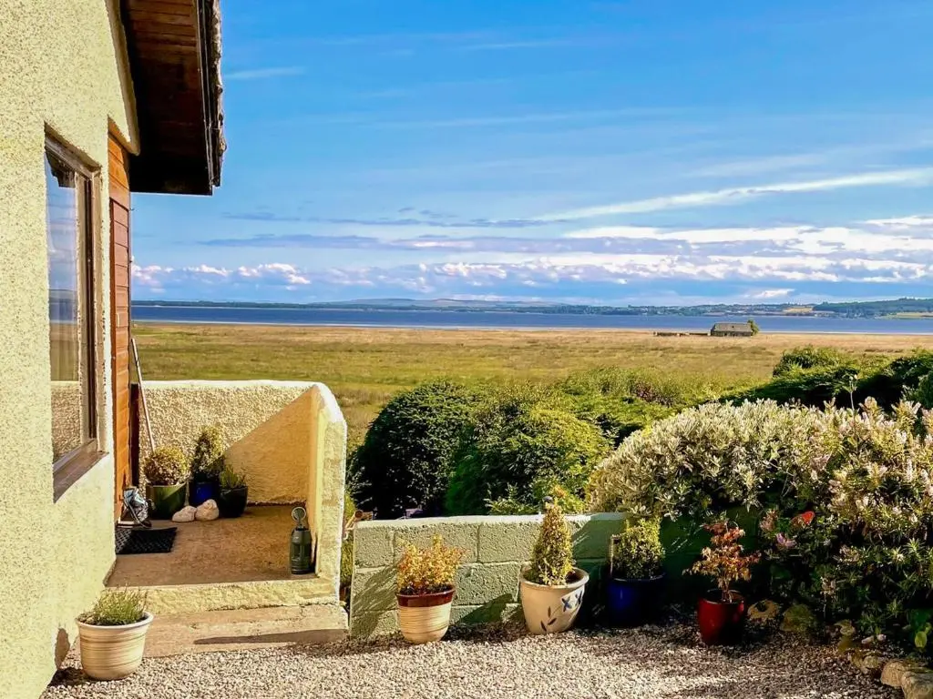 a balcony with potted plants and a view of a field at Achnacarry Cottage in Evelix