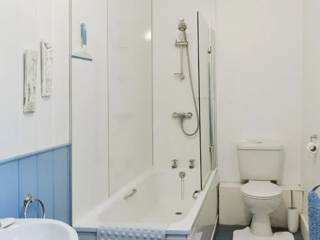 a bathroom with a tub and a toilet and a sink at Old Post Office House in Knockbain