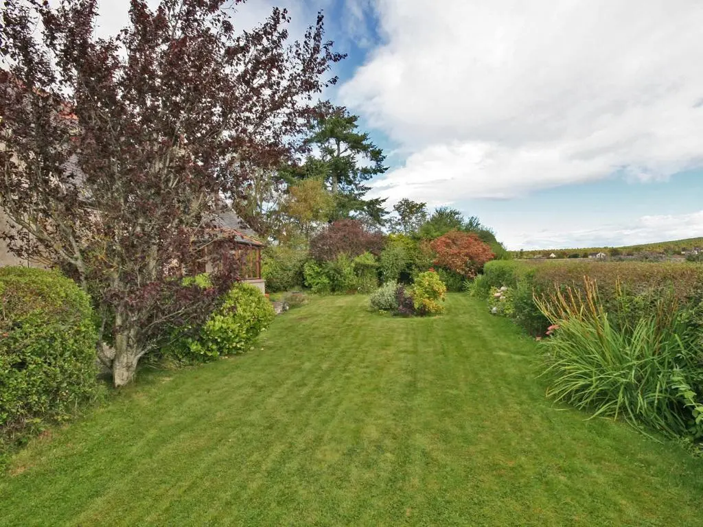 a garden with a green lawn and a tree at Old Post Office House in Knockbain