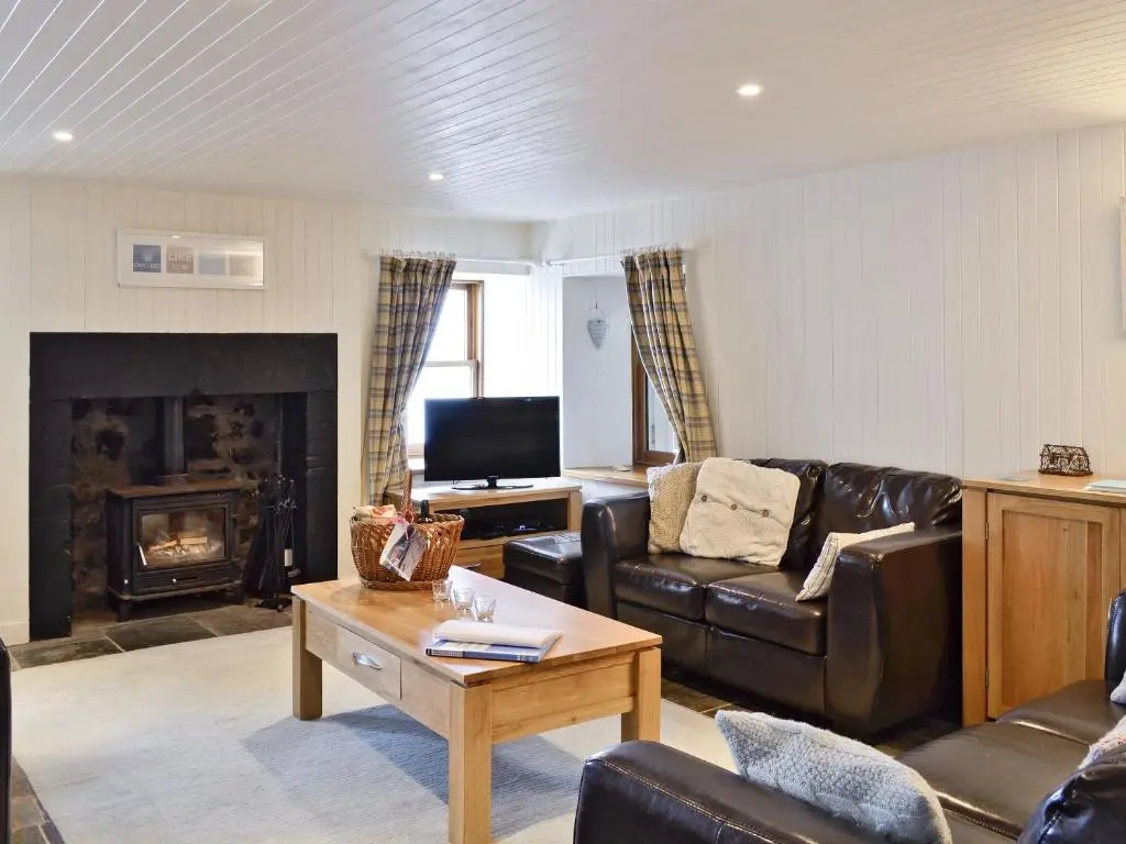 a living room with a couch and a fireplace at Crovie Cottage in Gardenstown