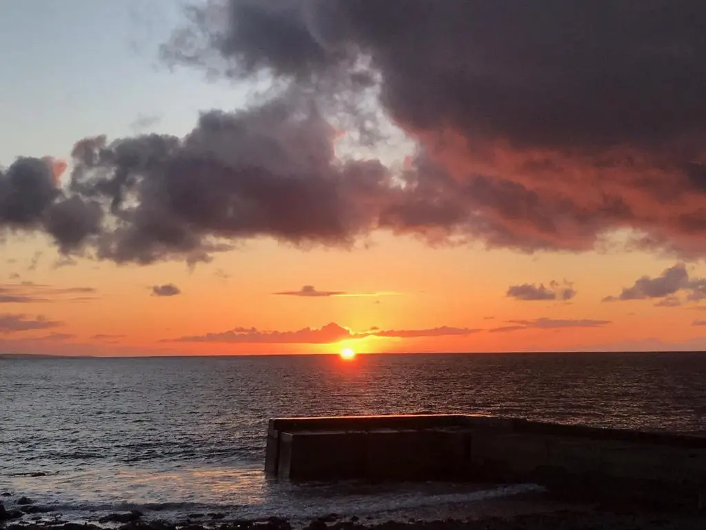 a sunset over the ocean with the sun setting at Crovie Cottage in Gardenstown
