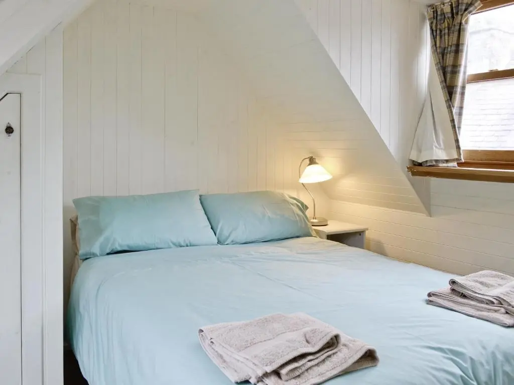 a bedroom with a blue bed with towels on it at Crovie Cottage in Gardenstown